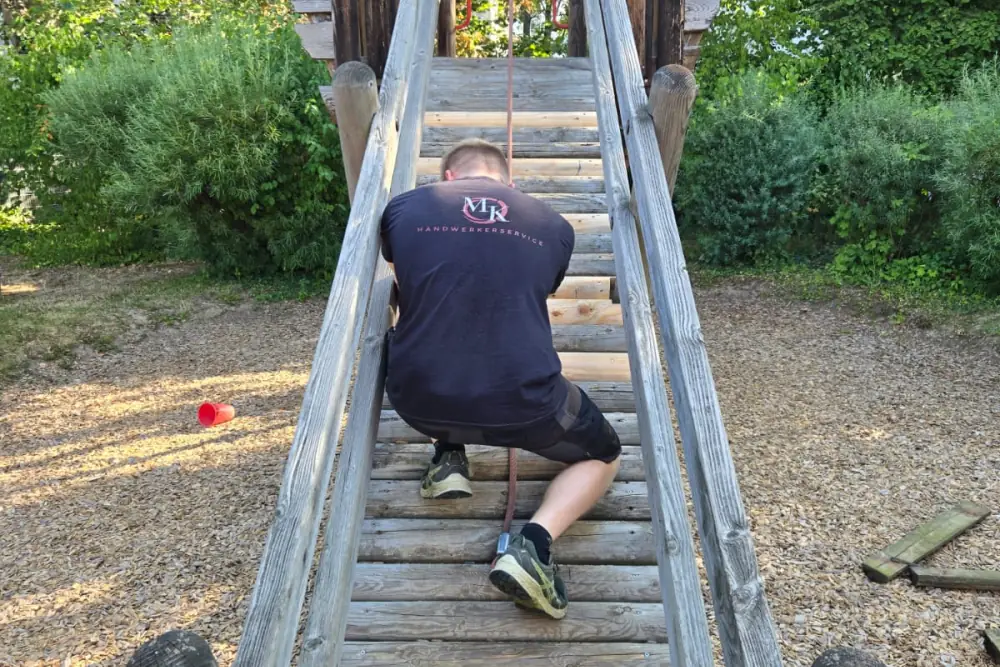 Marcel Käthner setzt neue Sprossen in die Holzleiter eines Spielgeräts