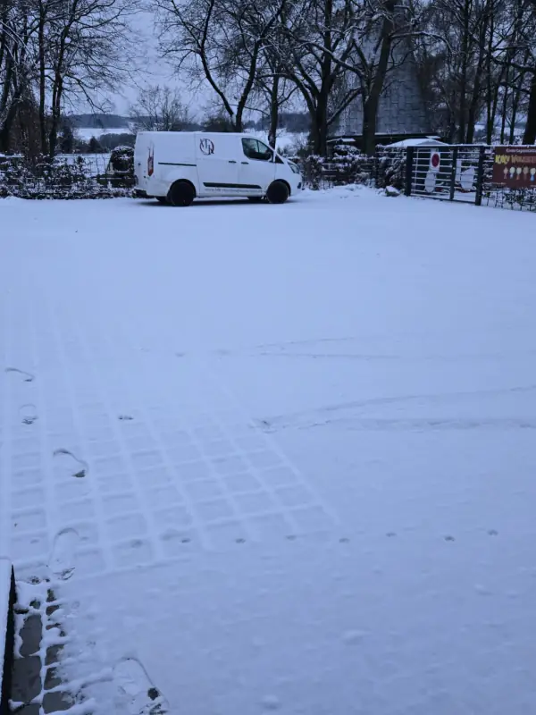 Verschneiter Parkplatz am frühen Morgen, hinten der Transporter von MK-Handwerkerservice