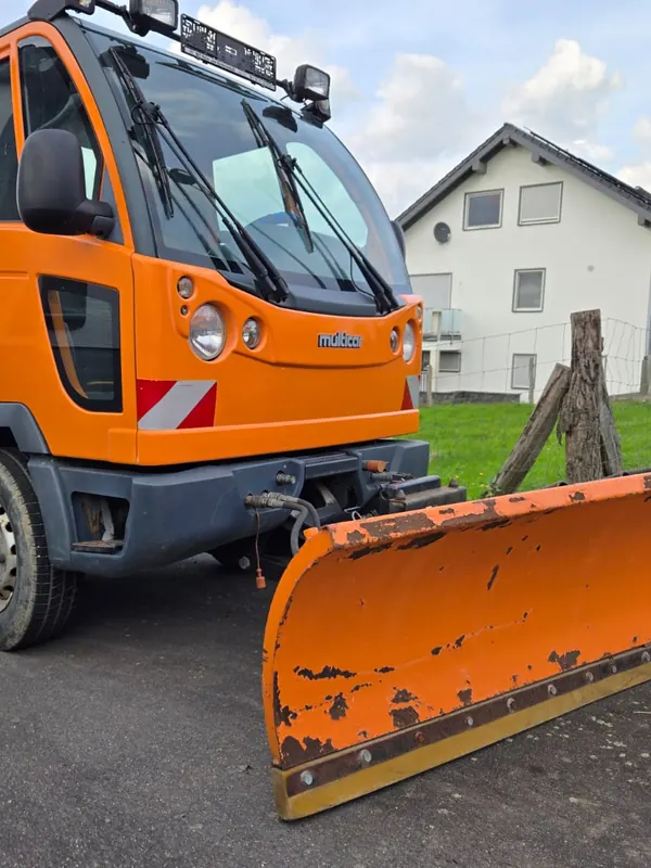 Orangefarbenes Räumfahrzeug von MK-Handwerkerservice mit montiertem Räumschild