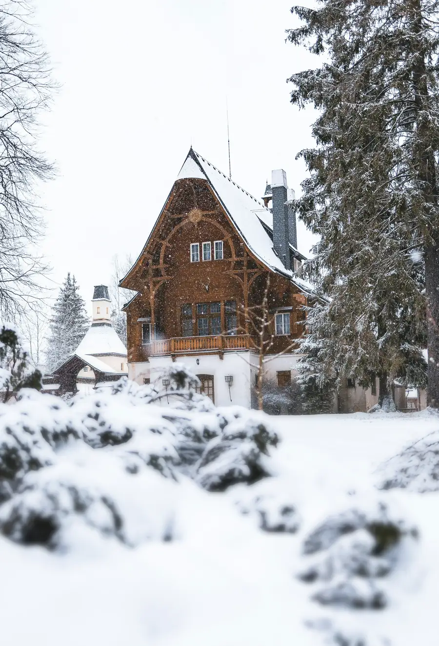 Verschneite Villa mit Holzgiebel zwischen hohen Tannen